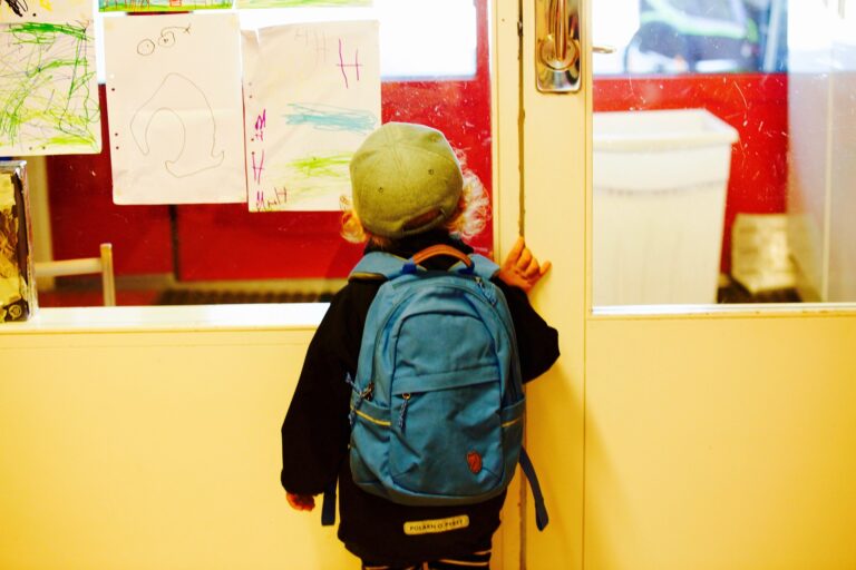 Un enfant à l'école avec son cartable sur le dos.